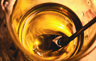 Amber liquid representing coal tar, used to illustrate the active ingredient in Polytar medicated scalp shampoo